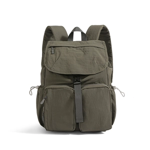 Detail of olive green nylon backpack featuring flap closure and multi-zip utility pockets
