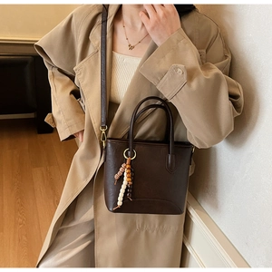 Detail of vintage brown tote bag with wooden bead pendant and slim adjustable shoulder strap