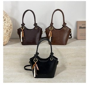 Detailed shot of retro bucket bags in three colors with wooden bead charms on stone stairs