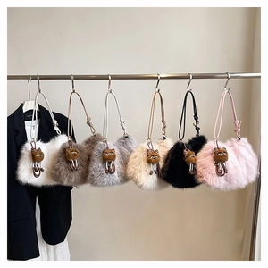 Detail view of large fuzzy plush shoulder bags in six colors with cat-shaped charms