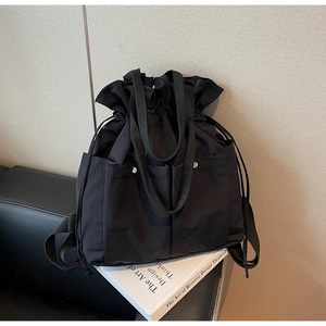 Detail of black multifunctional bucket backpack with drawstring and silver buckles