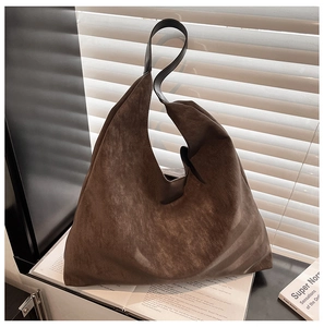 Close-up of minimalist dark brown matte suede tote bag with black leather shoulder strap