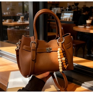 Détail du sac seau marron texturé avec fermoir tournant en métal et breloque en perles