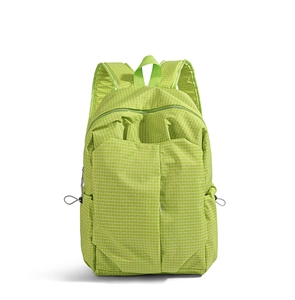 Detail view of lightweight green backpack showing fine white grid texture and side drawstring pocket