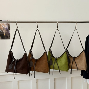 Row of four vintage matte leather crossbody bags in assorted earthy colors on hangers