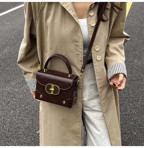Detail of dark brown leather crossbody bag with quilted pattern and gold oval lock