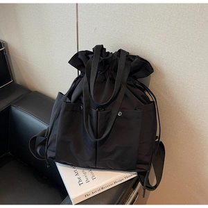 Detail of black drawstring bucket bag with snap pockets and wide webbing handles