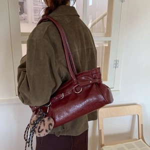 Détail du sac à bandoulière en cuir ciré bordeaux avec un élégant pompon à motif léopard