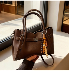 Détail du sac seau en cuir marron foncé avec fermoir argenté et pendentif de perles