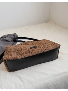 Détail d'un sac cabas léopard avec base en similicuir noir et étiquette de marque
