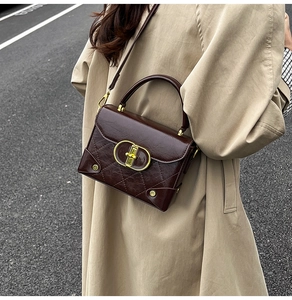 Detail of vintage brown quilted leather handbag with gold buckle on trench coat