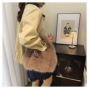 Dettaglio di una borsa a secchiello marrone in ecopelliccia abbinata a un outfit autunnale