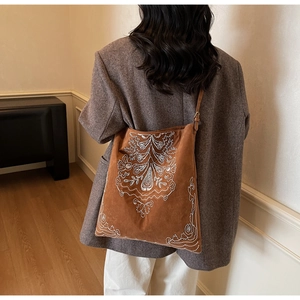 Detailansicht einer braunen Wildledertasche mit weißer Ethno-Stickerei auf der Vorderseite