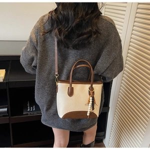 Detailed shot of retro cream and brown leather bucket bag with tassel accessory
