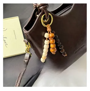 Detail of vintage brown leather bucket bag with three-color wooden bead pendant accessory