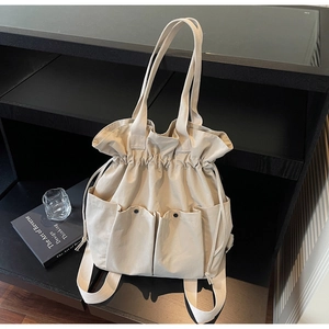 Detail of beige canvas bucket bag with drawstring closure and functional pockets