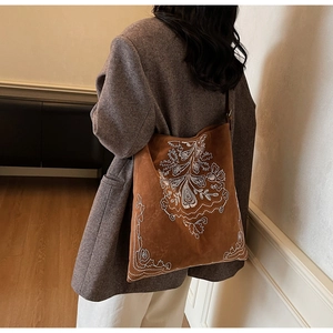 Detailansicht der braunen Wildleder-Tragetasche mit weißer Stickerei für elegantes Styling