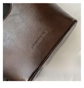 Macro detail of dark brown retro leather texture and embossed logo on the bucket bag