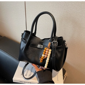 Détail du sac seau en cuir grainé noir avec fermoir rotatif argenté et pompon en bois