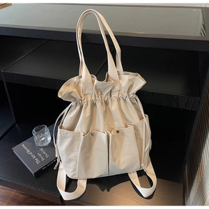 Detail of cream canvas bucket bag with drawstring closure and four symmetrical front pockets