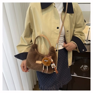 Detail of dark brown faux fur crescent bag with leather handle and plush doll charm