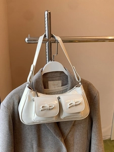 White faux leather shoulder bag with bow pockets displayed on a stylish hanger