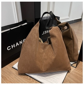 Macro view of brown suede tote bag with black leather straps on a wooden table