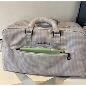 Detail der vorderen Reißverschlusstasche der grauen Reisetasche mit einem Handy