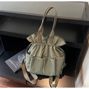 Detail view of khaki canvas bucket bag featuring drawstring closure and multiple utility pockets