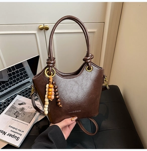 Detailed view of the dark brown oil wax leather bucket bag with a decorative beaded tassel