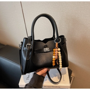 Gros plan sur un sac seau noir en cuir grainé avec fermoir rotatif et perles décoratives