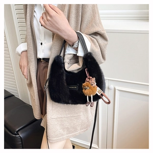 Detail of plush black dumpling bag with golden tag and cute bear pendant charm