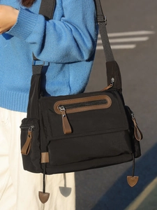 Retro black nylon messenger bag with brown leather accents and adjustable strap shown on model