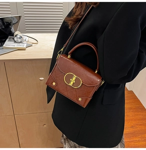 Detail of vintage dark brown crossbody bag with quilted texture and gold metal clasp