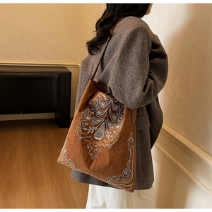 Detailaufnahme der braunen Wildledertasche mit weißer Stickerei und breitem Schultergurt