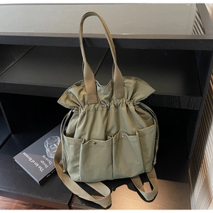 Close-up of khaki bucket bag with drawstring closure and silver magnetic buckle pockets