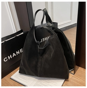 Detail of vintage matte black hobo tote bag featuring premium texture on wooden table