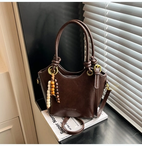 Detail of soft brown leather bucket bag with wooden beads and brand logo on design book