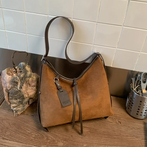 Detailed view of vintage caramel suede hobo bag with fringe on a wooden surface