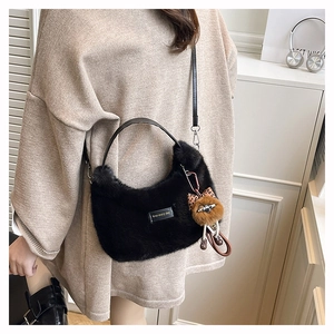 Detail of black faux fur crescent bag featuring a love every day patch and cute plush charm
