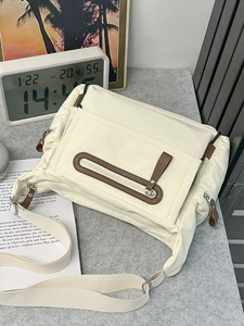 Minimalist beige messenger bag with brown leather trim and wide adjustable strap