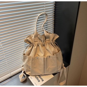 Detail of beige canvas bucket bag with drawstring closure and two front button pockets
