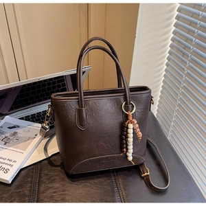 Detailed close-up of retro dark brown PU leather bucket bag with wooden bead charms