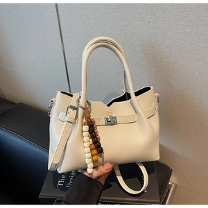 Détail du sac à main crème avec fermeture à torsion métallique et pendentif en perles