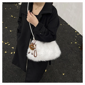 Close-up of white plush crossbody bag with cute brown doll pendant on black wool coat