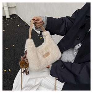 Detail of plush beige dumpling bag with leopard bow charm and leather handle