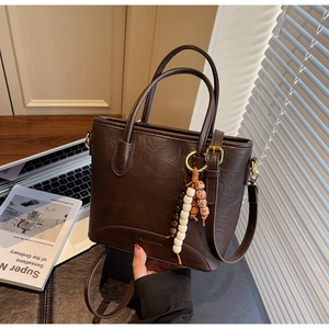 Close-up of brown retro tote bag with leather texture and boho beaded charm detail