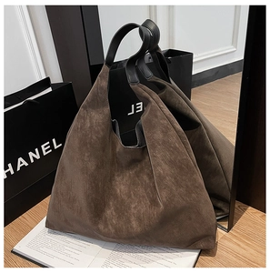 Close-up of brown matte tote bag with black straps and soft suede texture by a mirror