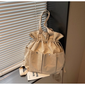 Detail of beige bucket bag with drawstring closure and multiple utility snap pockets