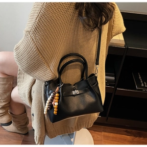 Détail du sac seau en cuir noir grainé avec fermoir rotatif argenté et breloque